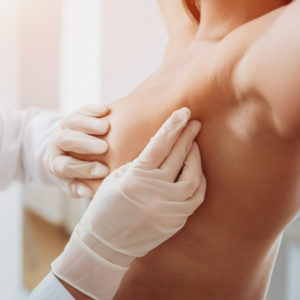 Ärztin untersucht die Brust einer Patientin vor einer Brustkorrektur oder Brustwarzenkorrektur